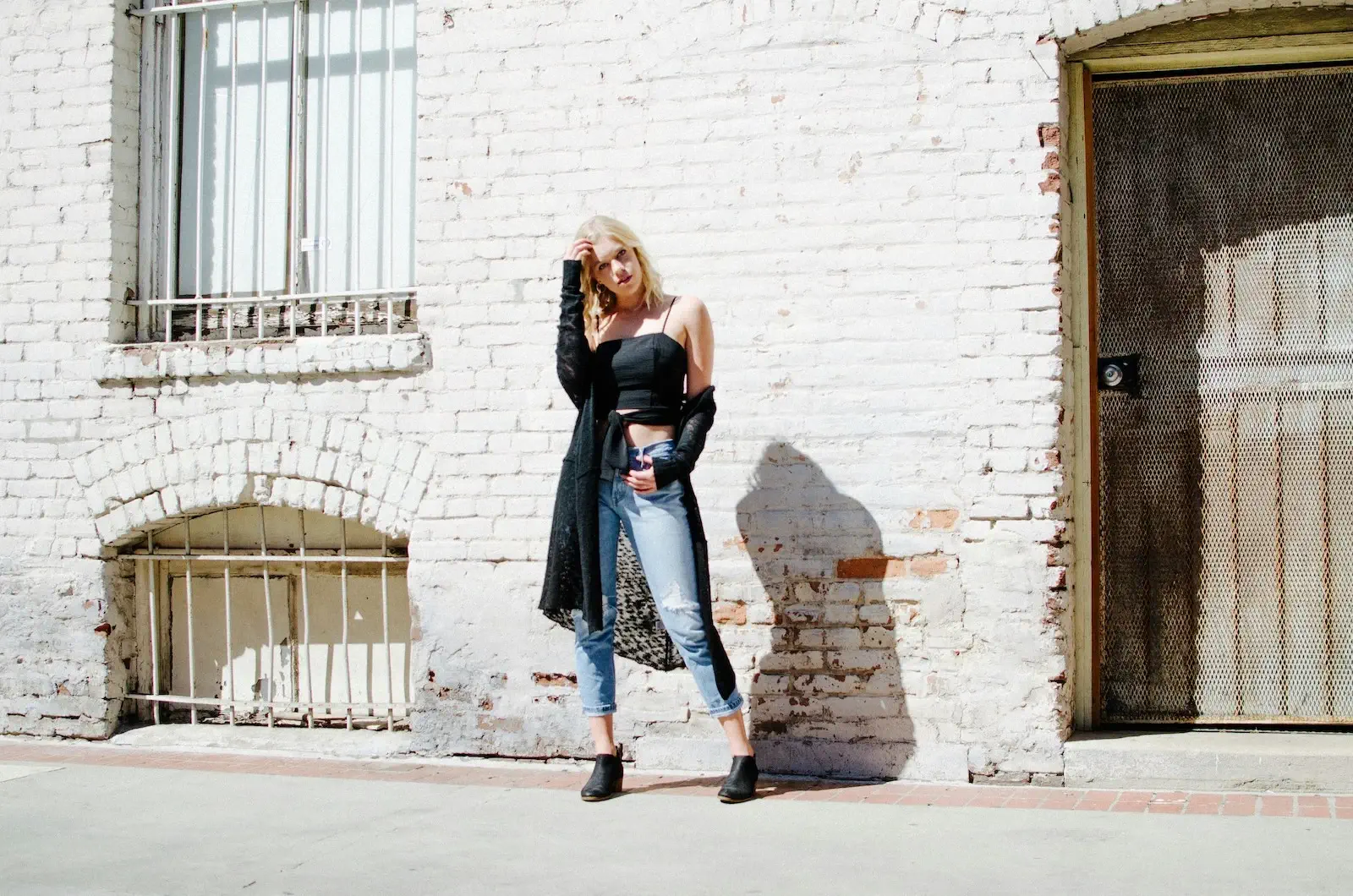 woman dressed fashionably against a whitewashed brick wall