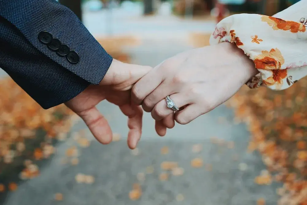 man and woman holding hands, showing off engagement ring