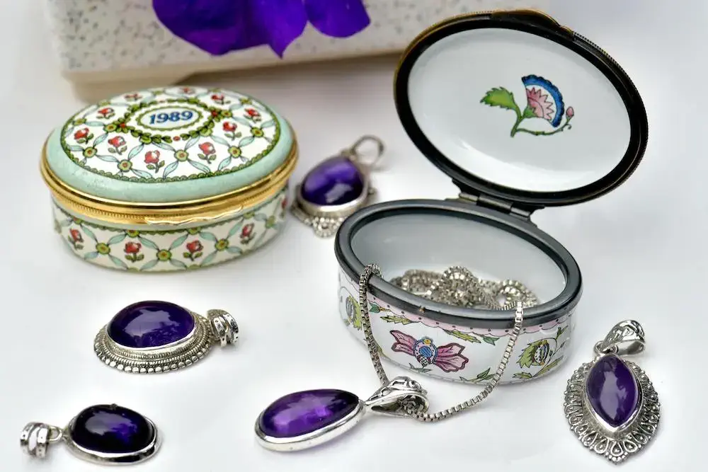a variety of purple jewelry pieces along with decorative jewelry boxes