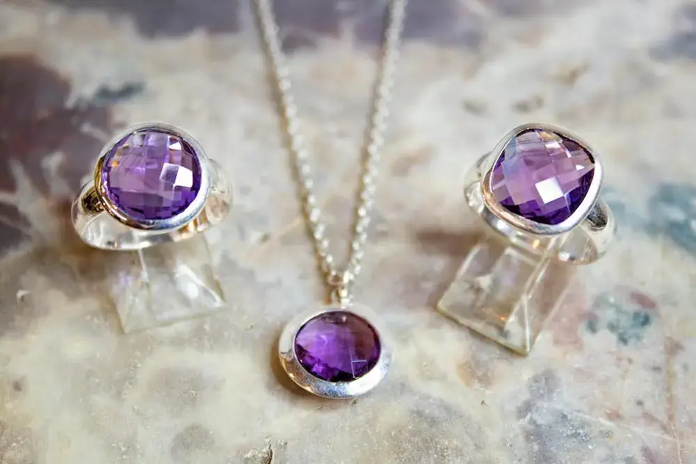 close-up image showing a pair of amethyst rings and a necklace
